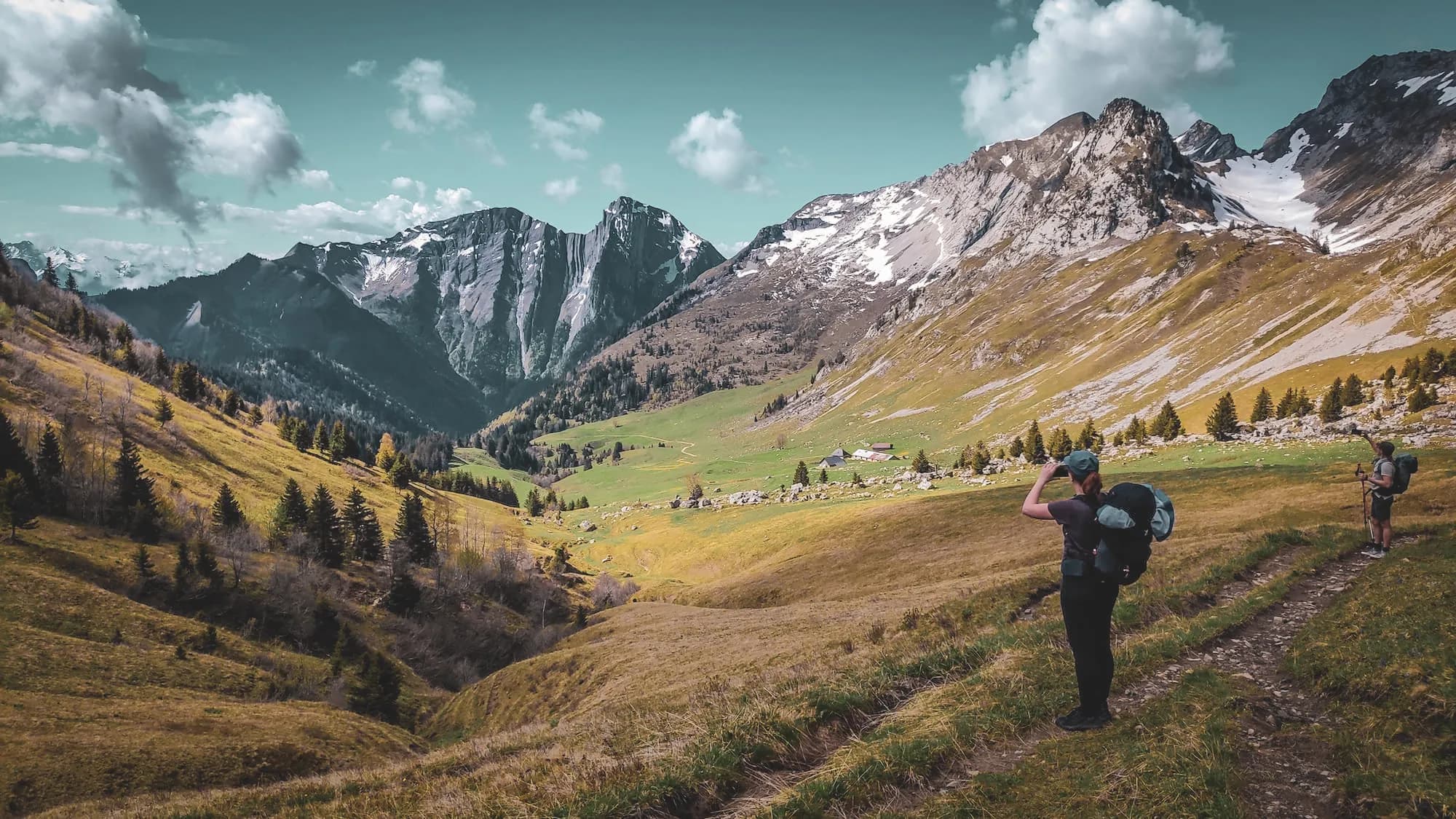 Hikers admiring the majestic mountains of the Hautes Bauges under a bright sky.