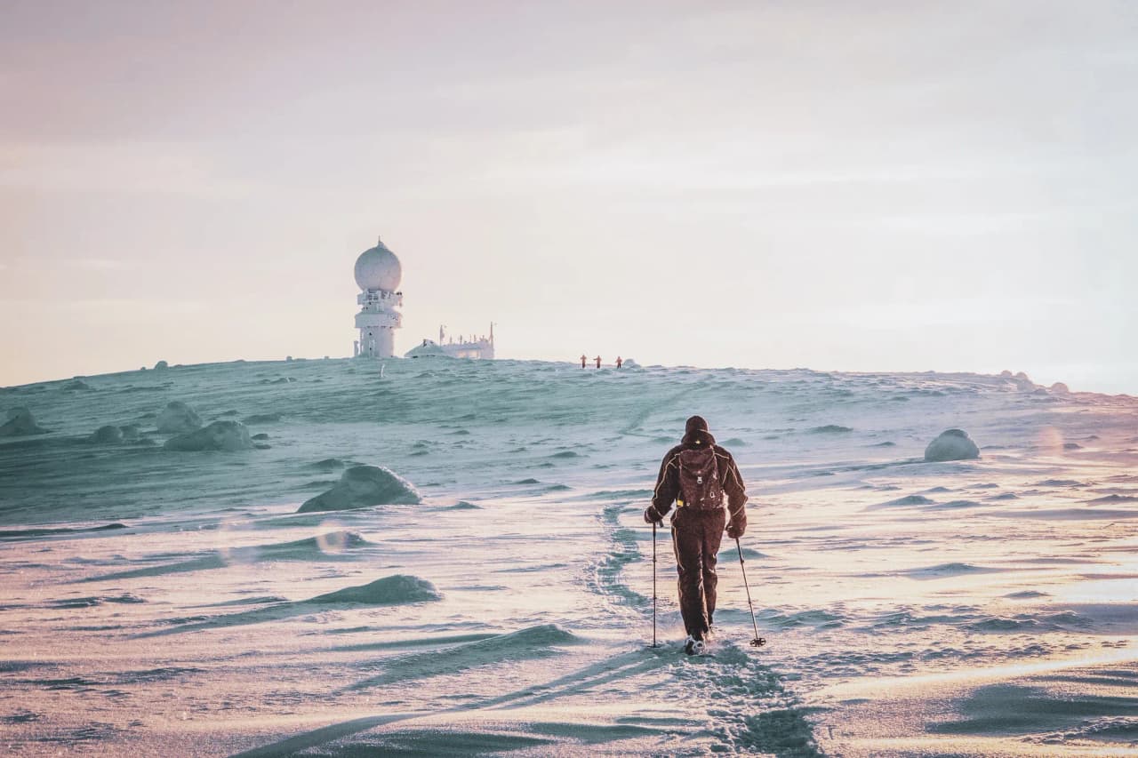 Un randonneur solennel marche sur la neige, face à une majestueuse expédition en Laponie.