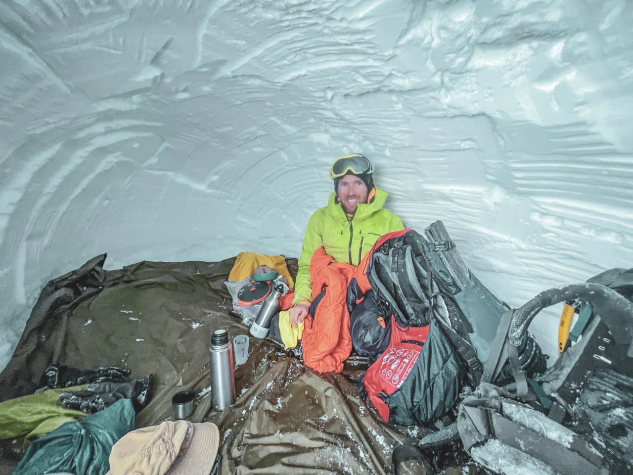Een gelukkige avonturier in een iglo, omringd door sneeuw, klaar voor een sterrennacht in de bergen.