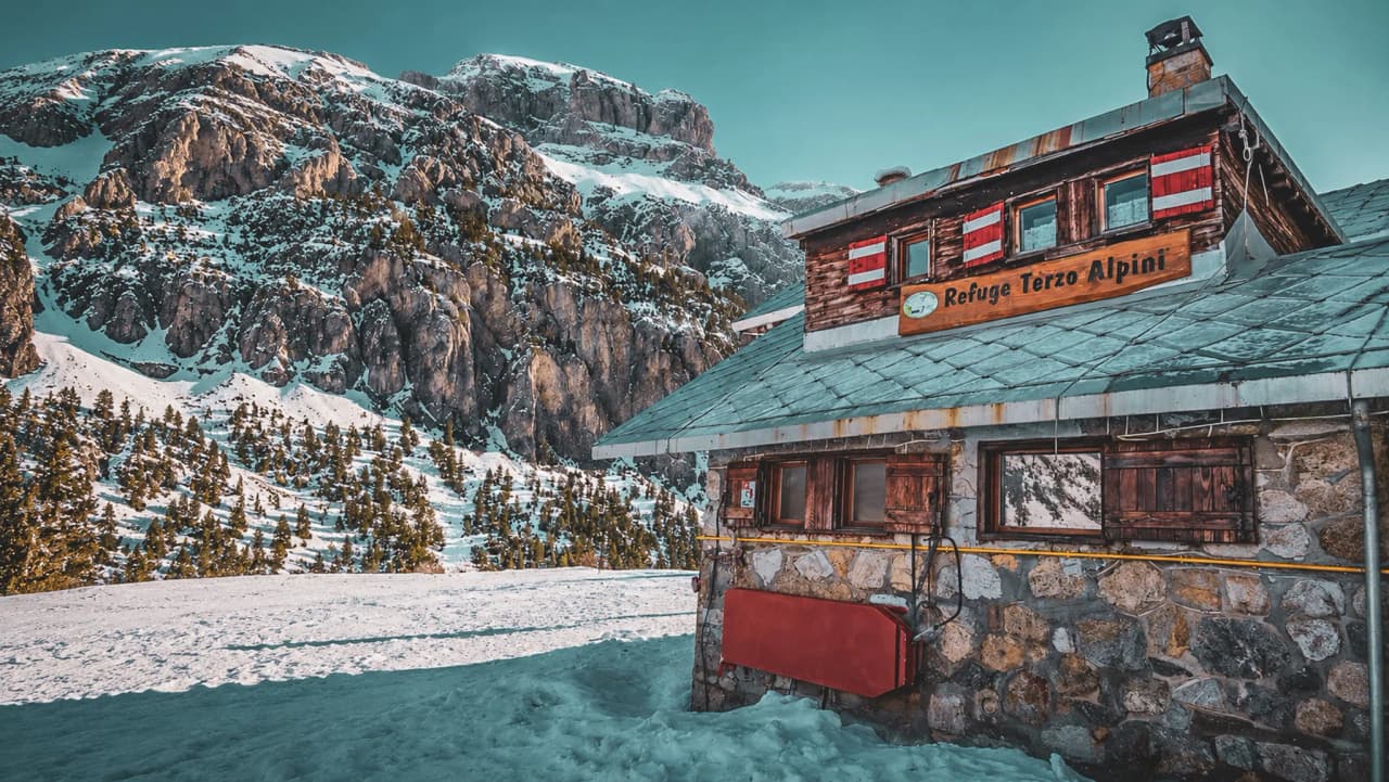 Een gezellige berghut, omringd door besneeuwde bergtoppen, die uitnodigt tot een avontuur in de Alpen.