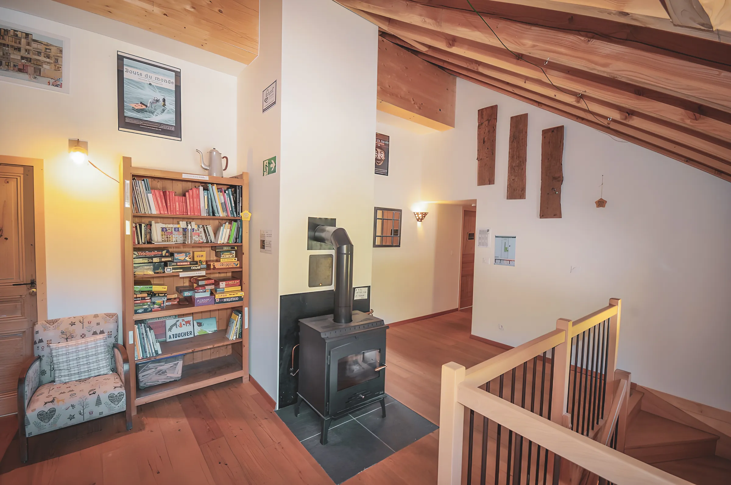 Het gezellige interieur van een houten chalet, met boekenkast, houtkachel en zachte verlichting.