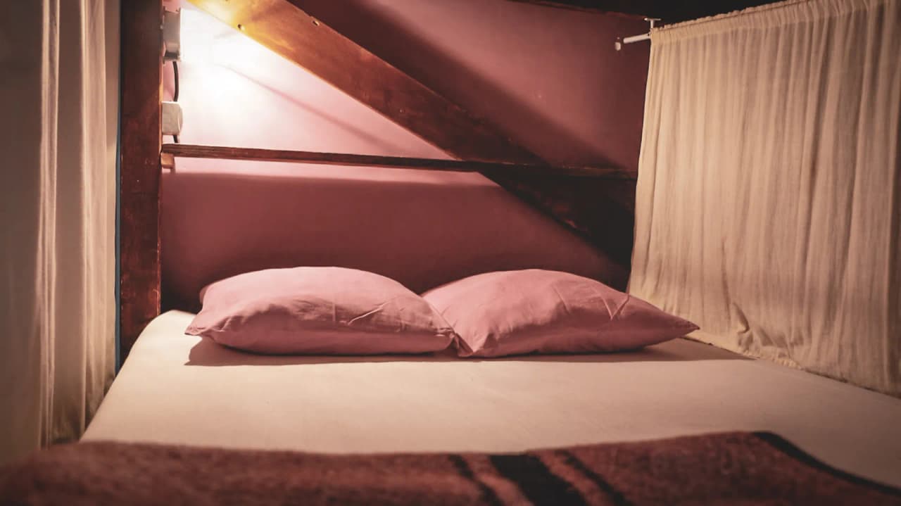 A comfortable bed under wooden beams, perfect for resting after a hike.
