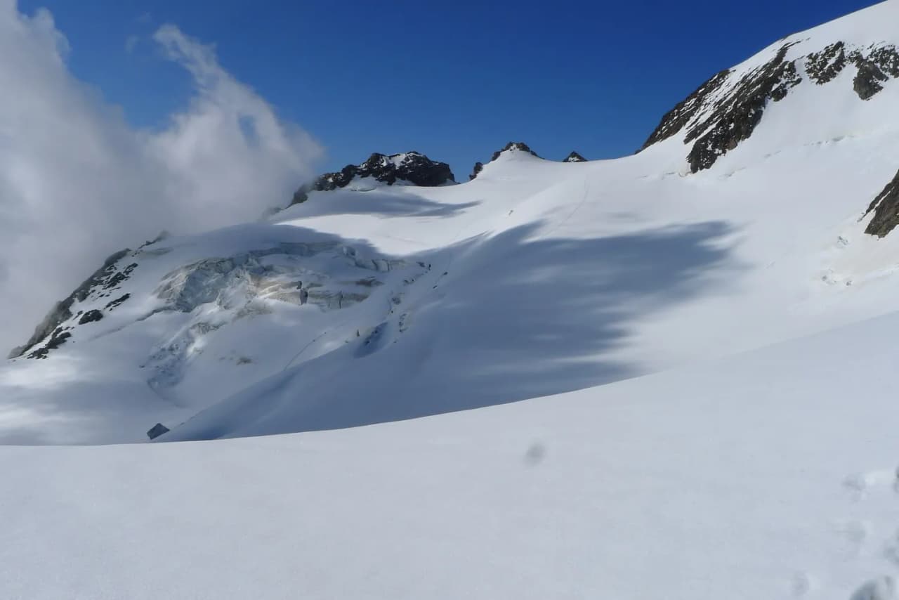 Majestic Alpine scenery, snow-capped mountains under a blue sky, an invitation to adventure.