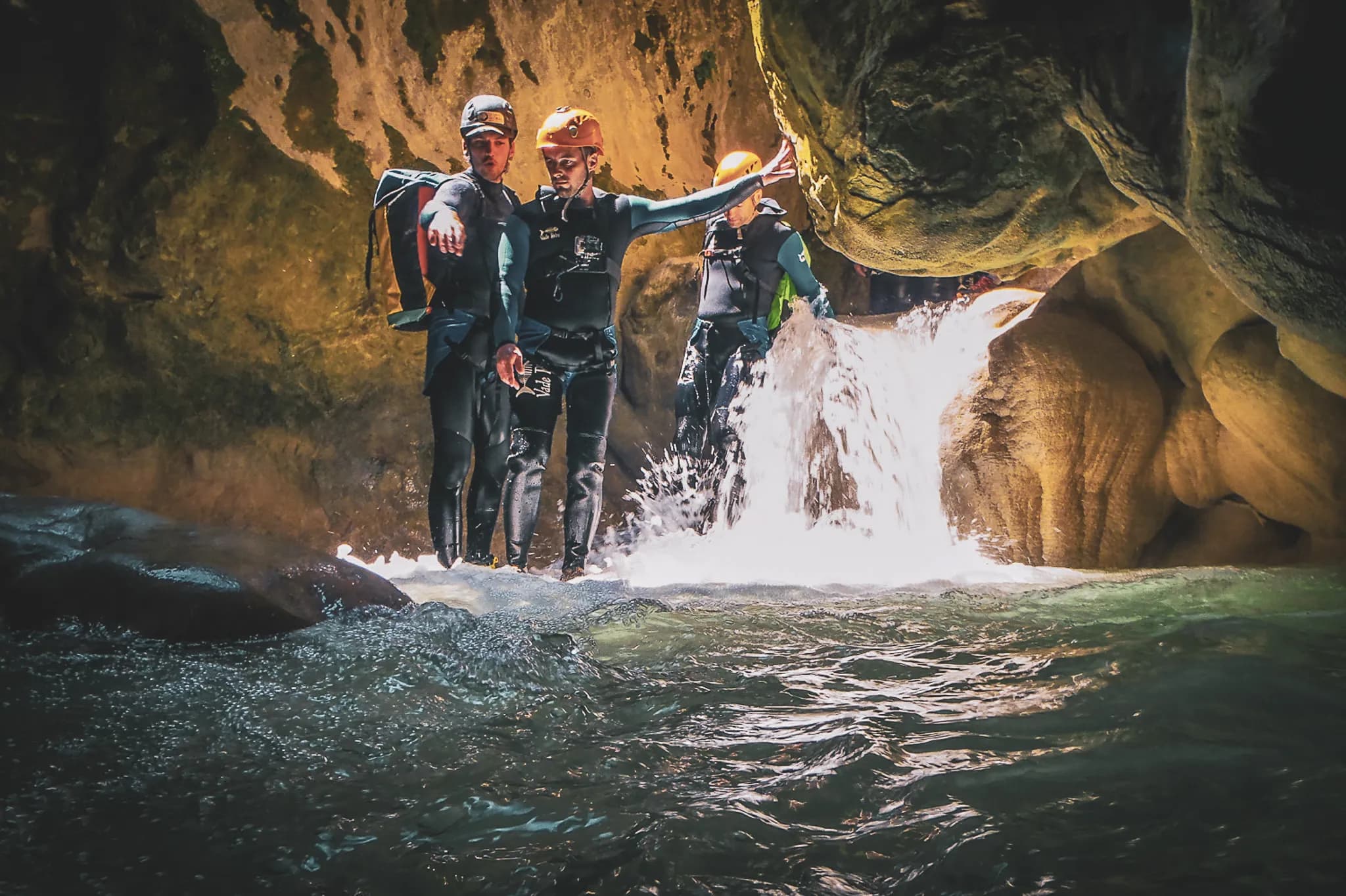 Group of adventurers in wetsuits in a canyon, ready for canyoning at the water's edge.