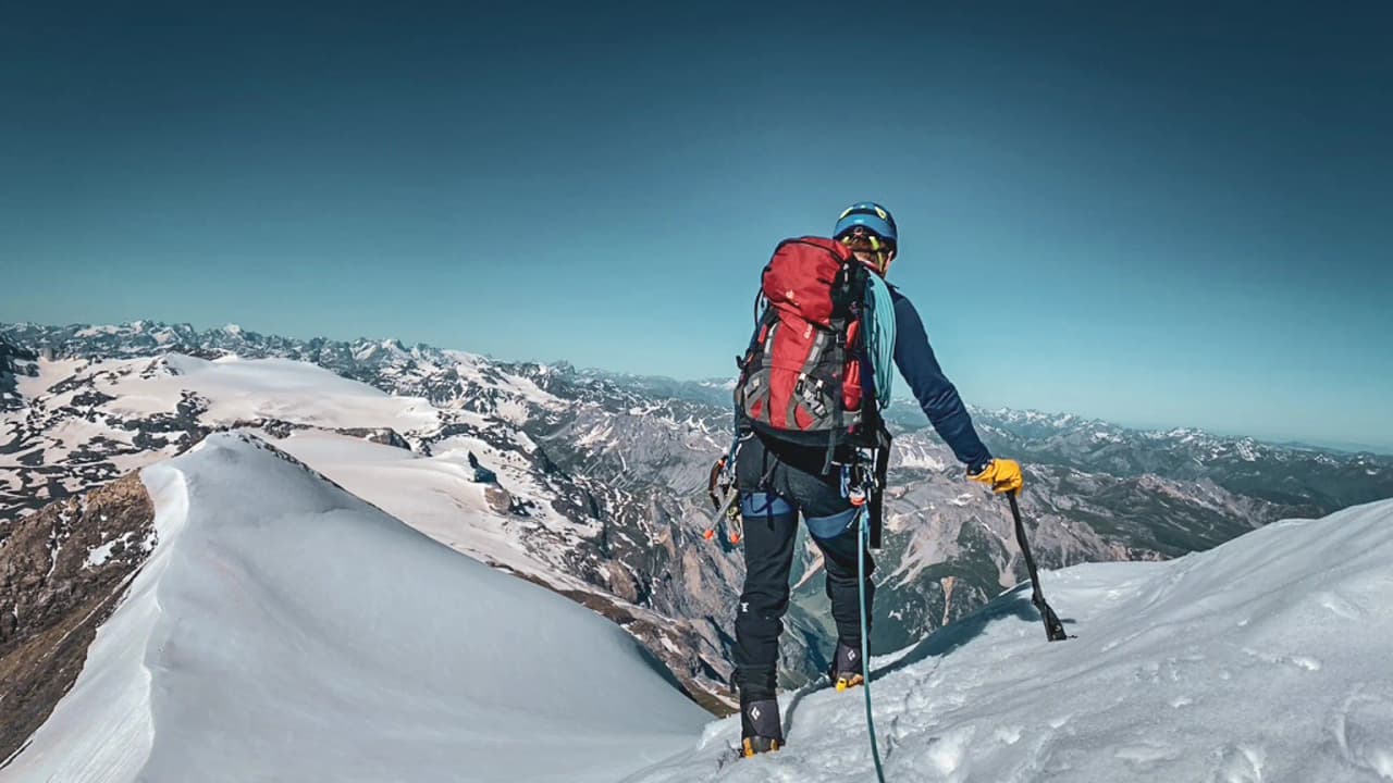 Alpiniste contemplant un panorama époustouflant depuis un sommet enneigé à Chamonix.