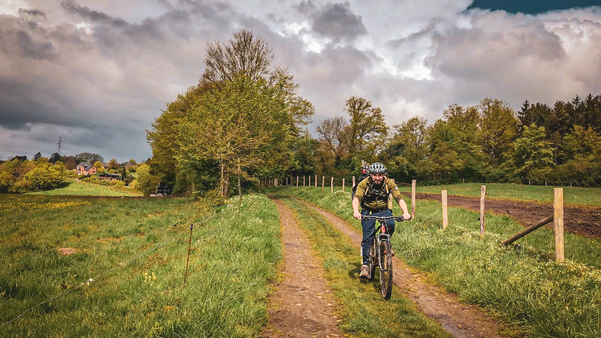 Un cycliste enthousiaste pédale sur un chemin verdoyant, entouré de forêts luxuriantes.