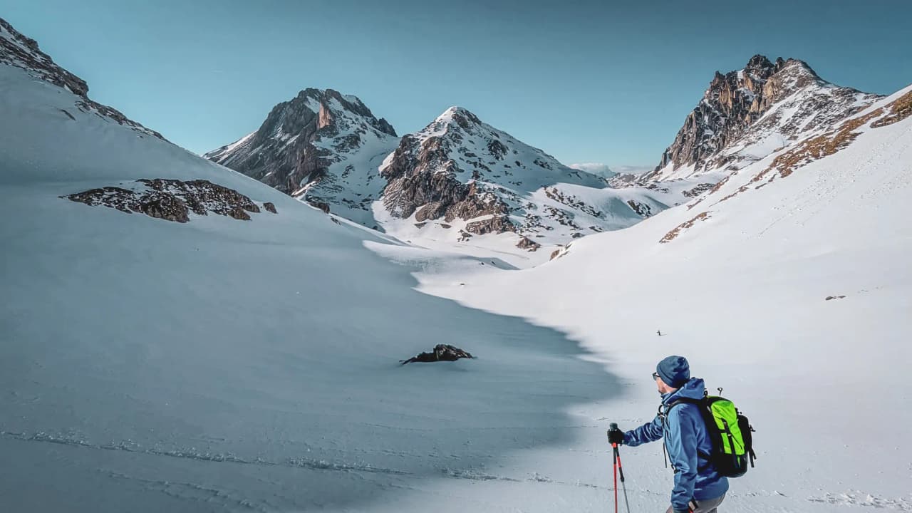 A hiker admiring a snow-covered alpine landscape, surrounded by majestic peaks in the Massif des Cerces.