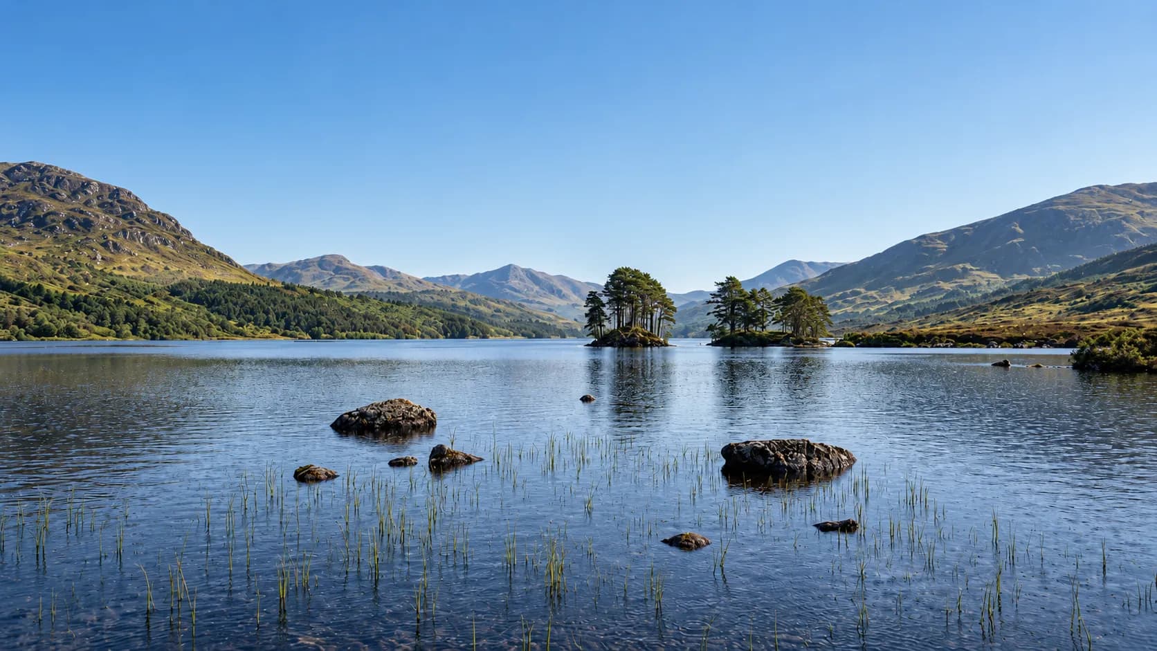 Een rustig meer, omringd door groene bergen, ideaal voor een uitstapje naar de Schotse Hooglanden.