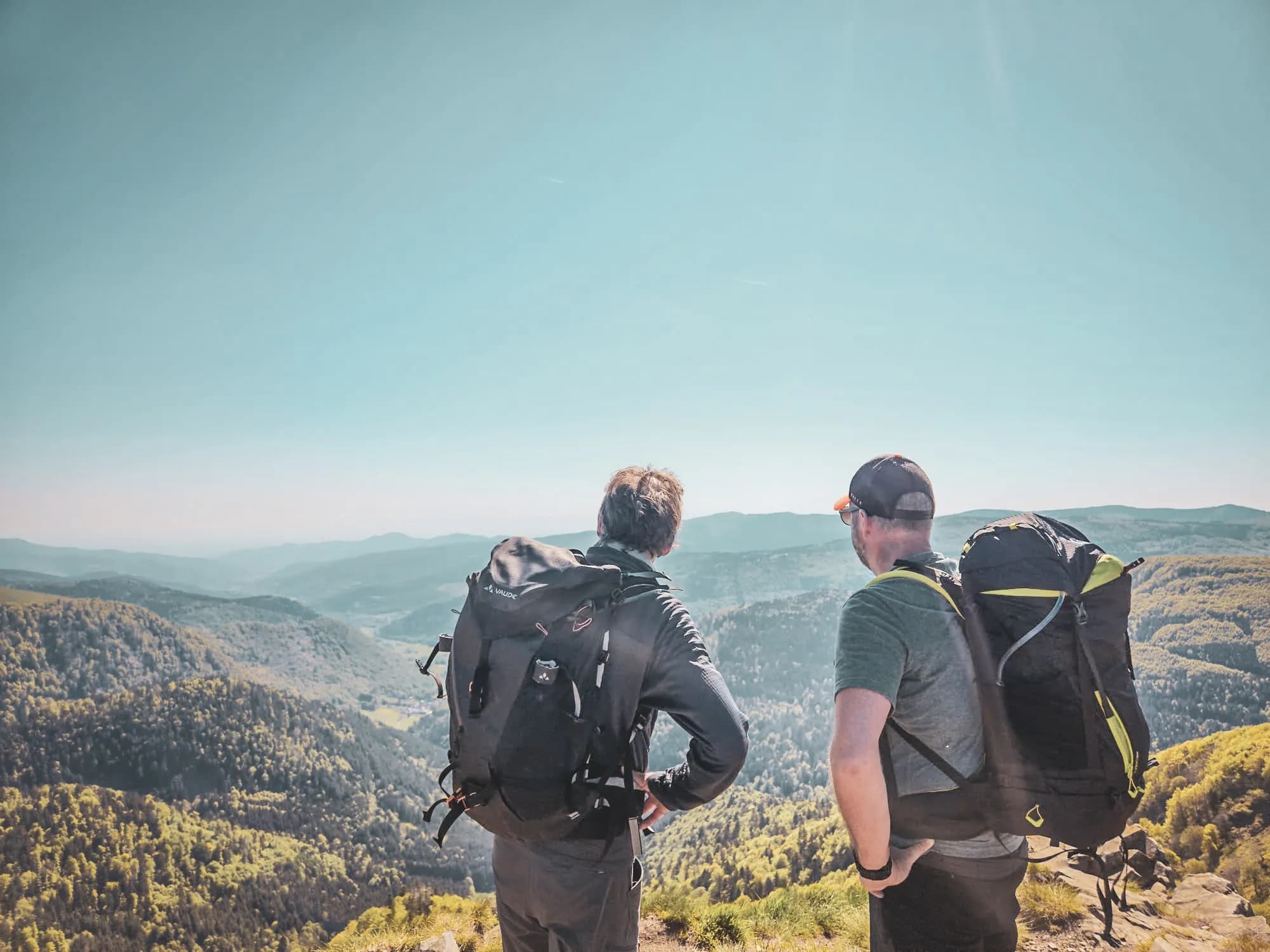 Deux randonneurs admirent un panorama verdoyant des Vosges, prêts pour l'aventure.