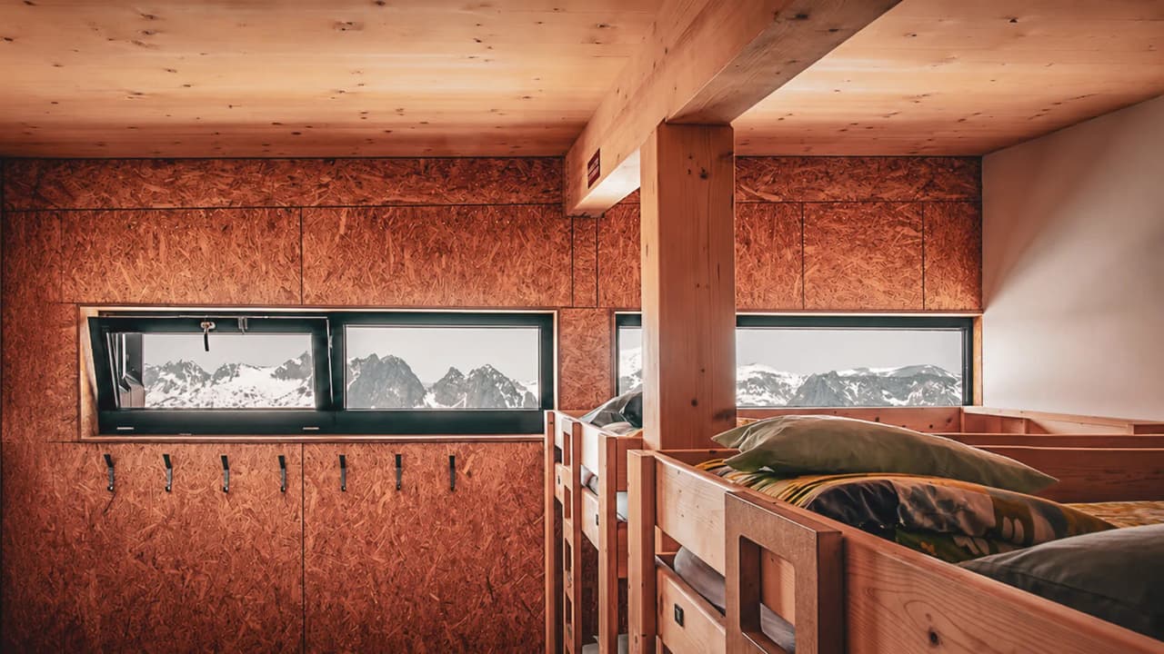 A cosy wooden interior with bunk beds and incredible mountain views.