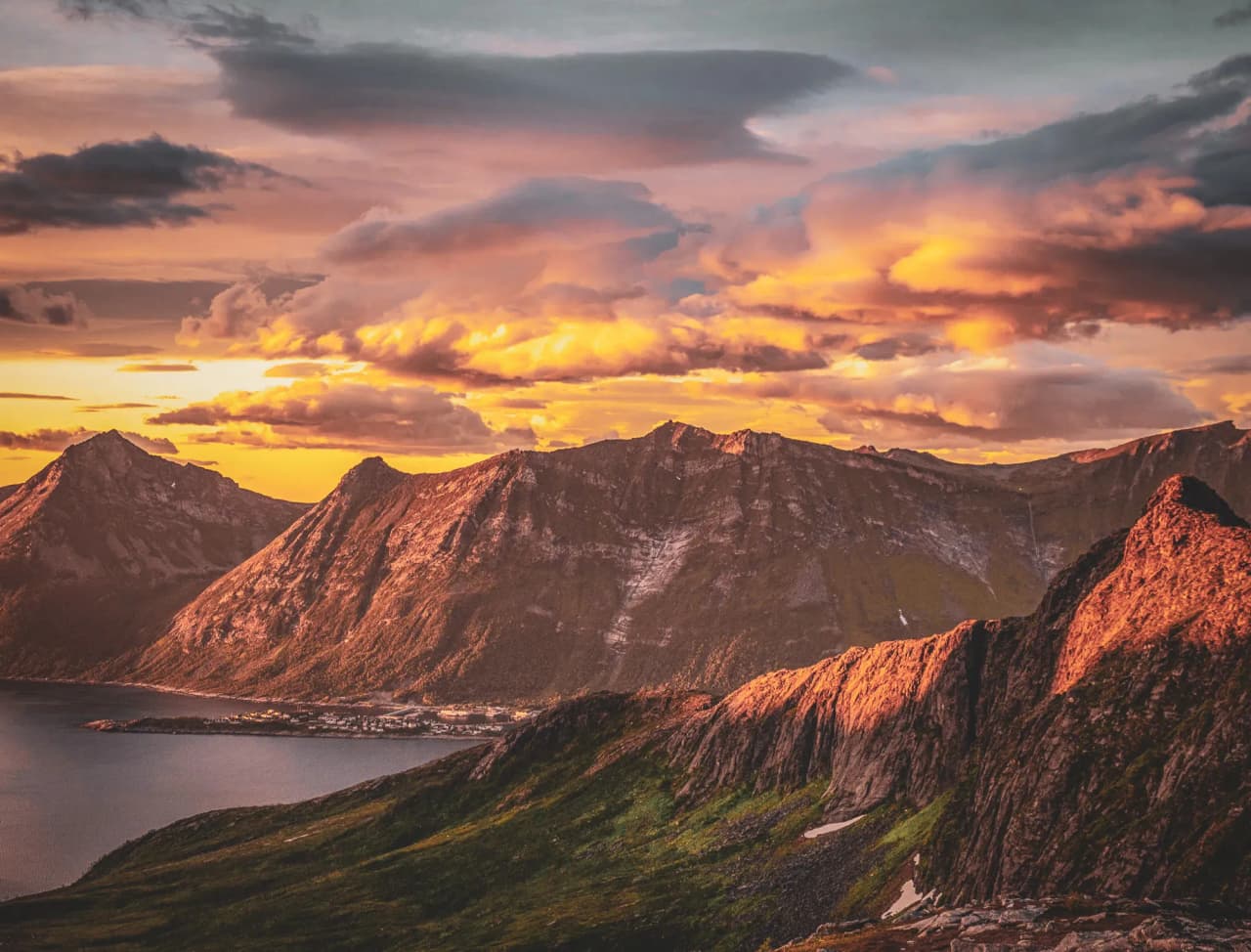 Spectaculaire zonsondergang over de bergen van het eiland Senja, omringd door majestueuze fjorden.