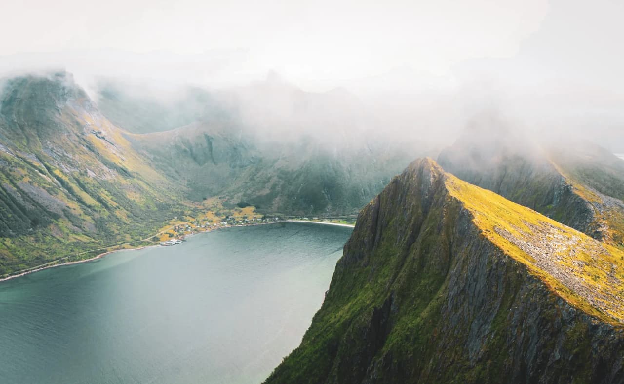Majestueuze bergen rondom een rustige fjord, badend in mist en zacht licht.