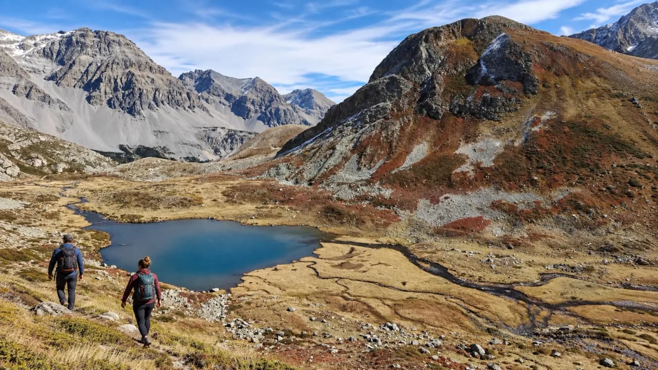 Randonneurs dans les Alpes, entourés de montagnes majestueuses et d'un lac scintillant.