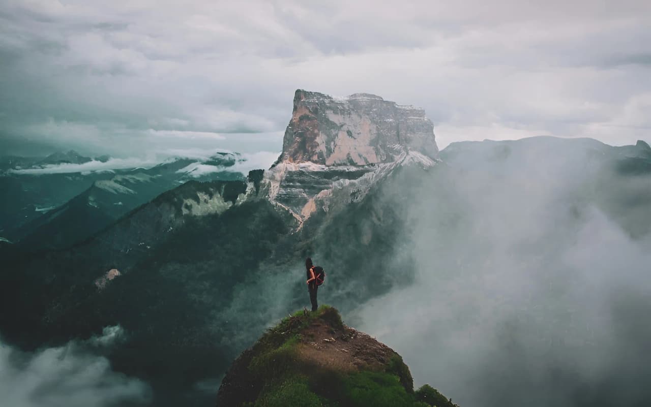 Man contemplating a vast, misty mountain landscape in the Vercors Highlands.