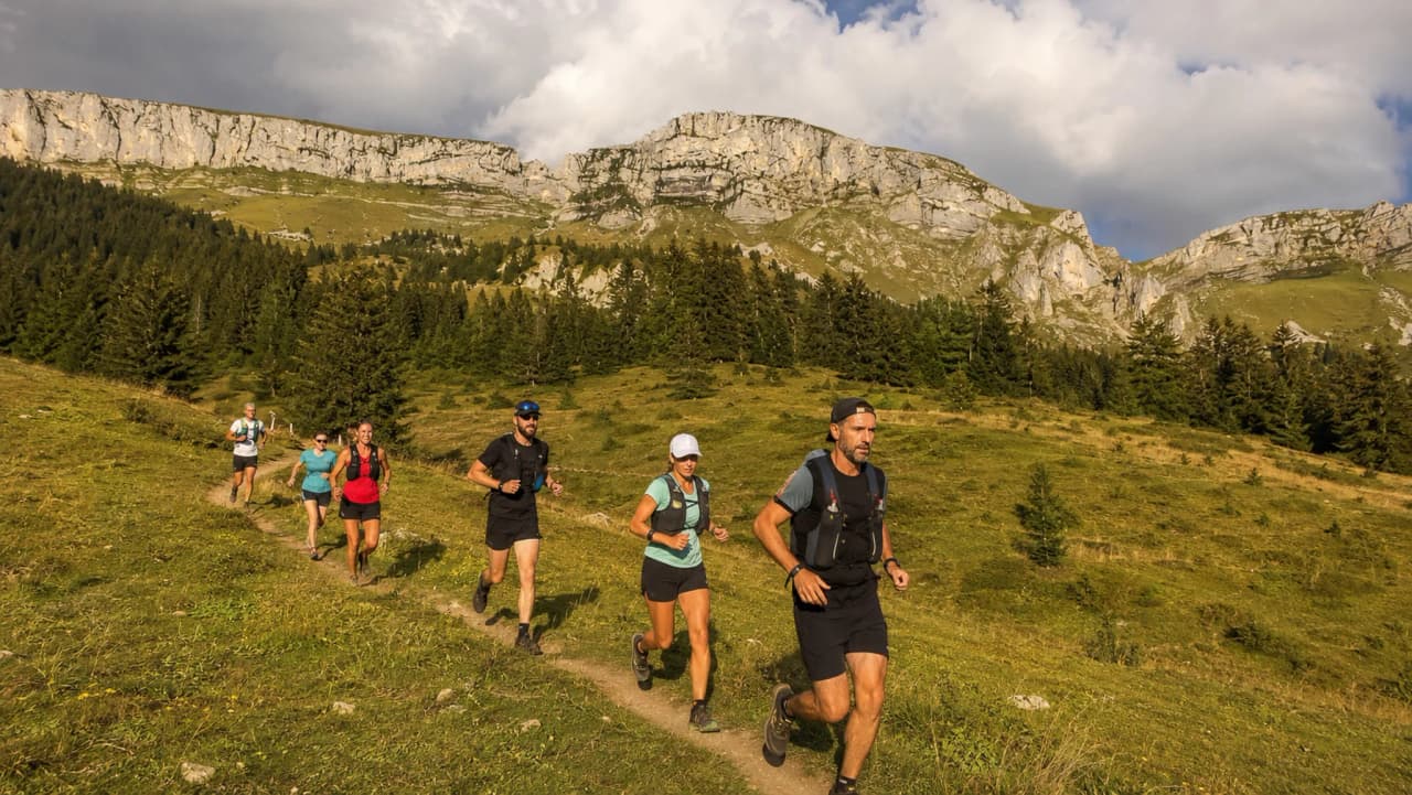 Groupe de coureurs en pleine nature, avec les montagnes de Chartreuse en arrière-plan.