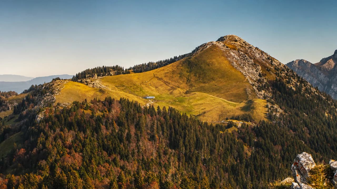 Un paysage montagneux en Chartreuse, vallées verdoyantes et sommets majestueux sous un ciel clair.
