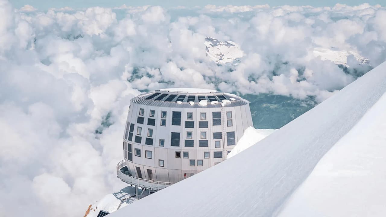 Een modern Berghut op de top van de Mont Blanc, omgeven door majestueuze wolken en besneeuwde landschappen.