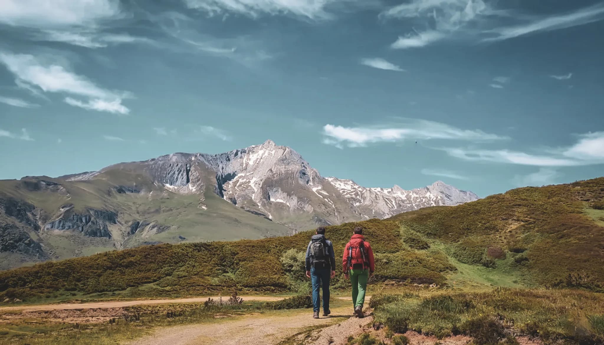 Wandelaars in een Pyrenees berglandschap, onder een stralend blauwe hemel.