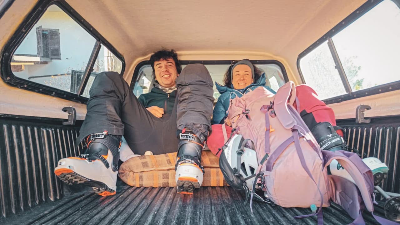 Un couple détendu dans le coffre d'un pick-up, prêt pour leur aventure de ski autour du Mont Viso.