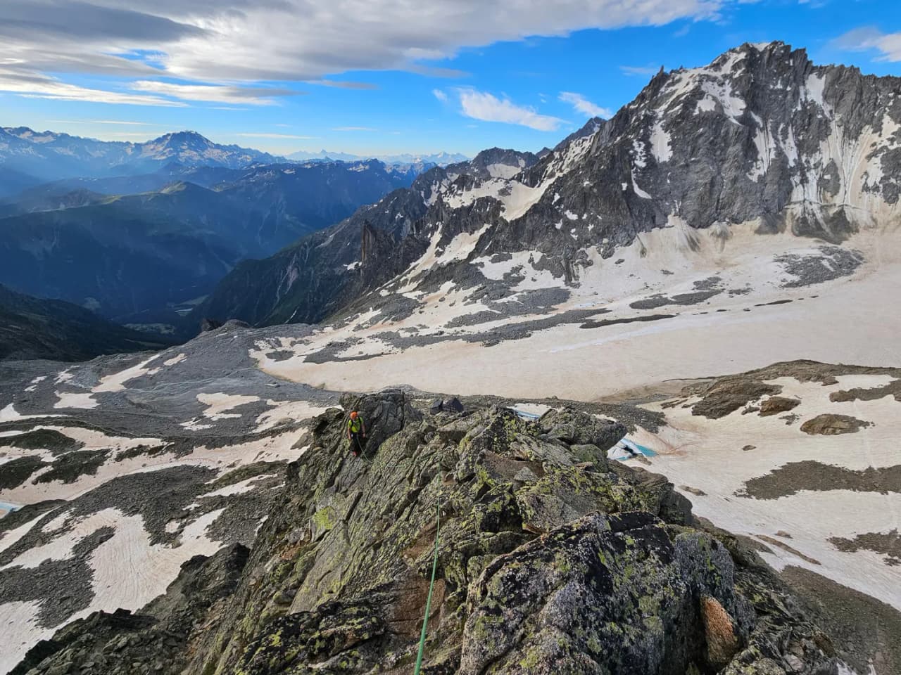 A breathtaking panoramic view of the Chamonix mountains, with a mountaineer in the middle of a climb.