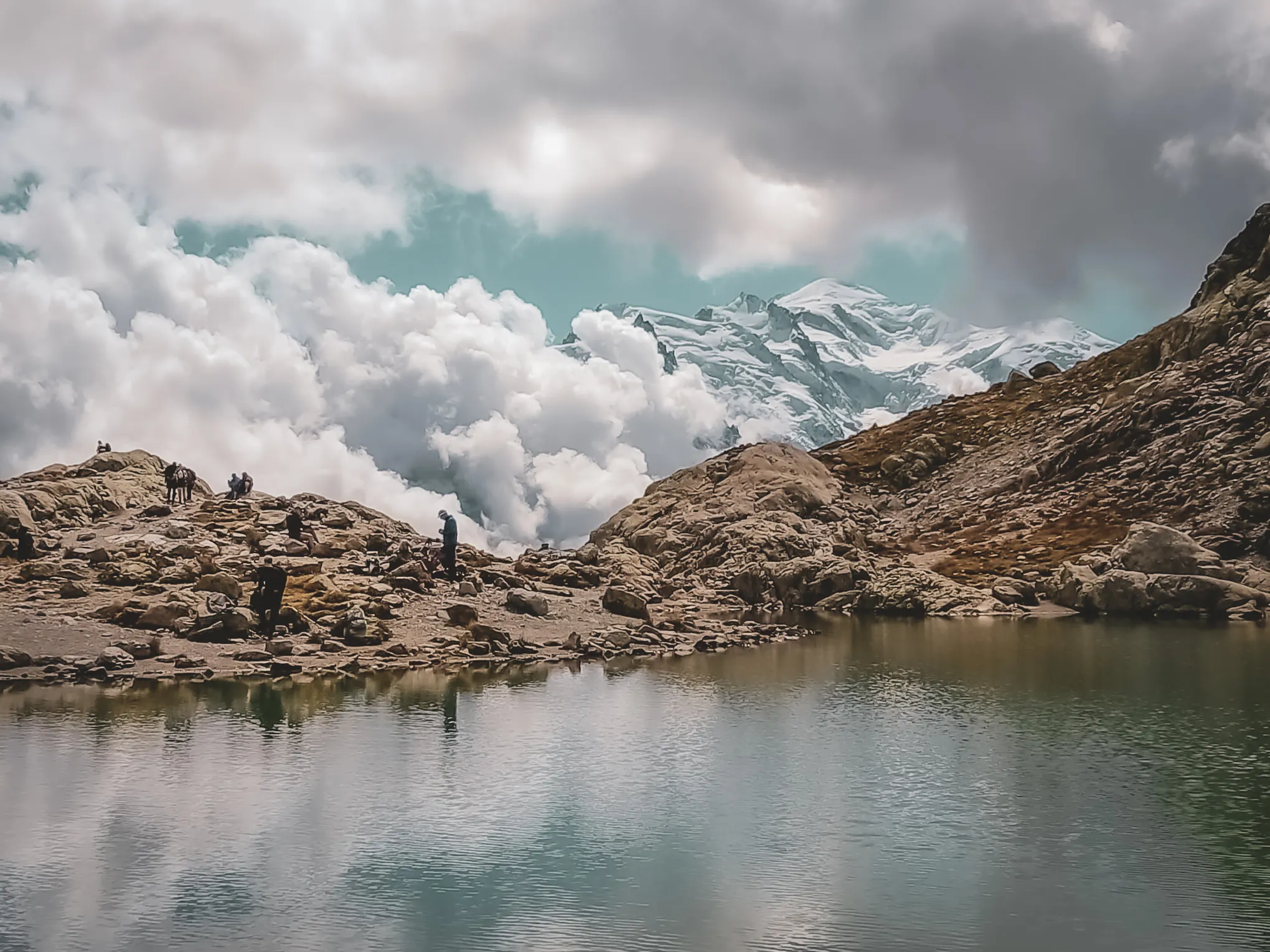 Een spectaculair Alpenpanorama met een ijskoud meer, besneeuwde bergen en majestueuze wolken.