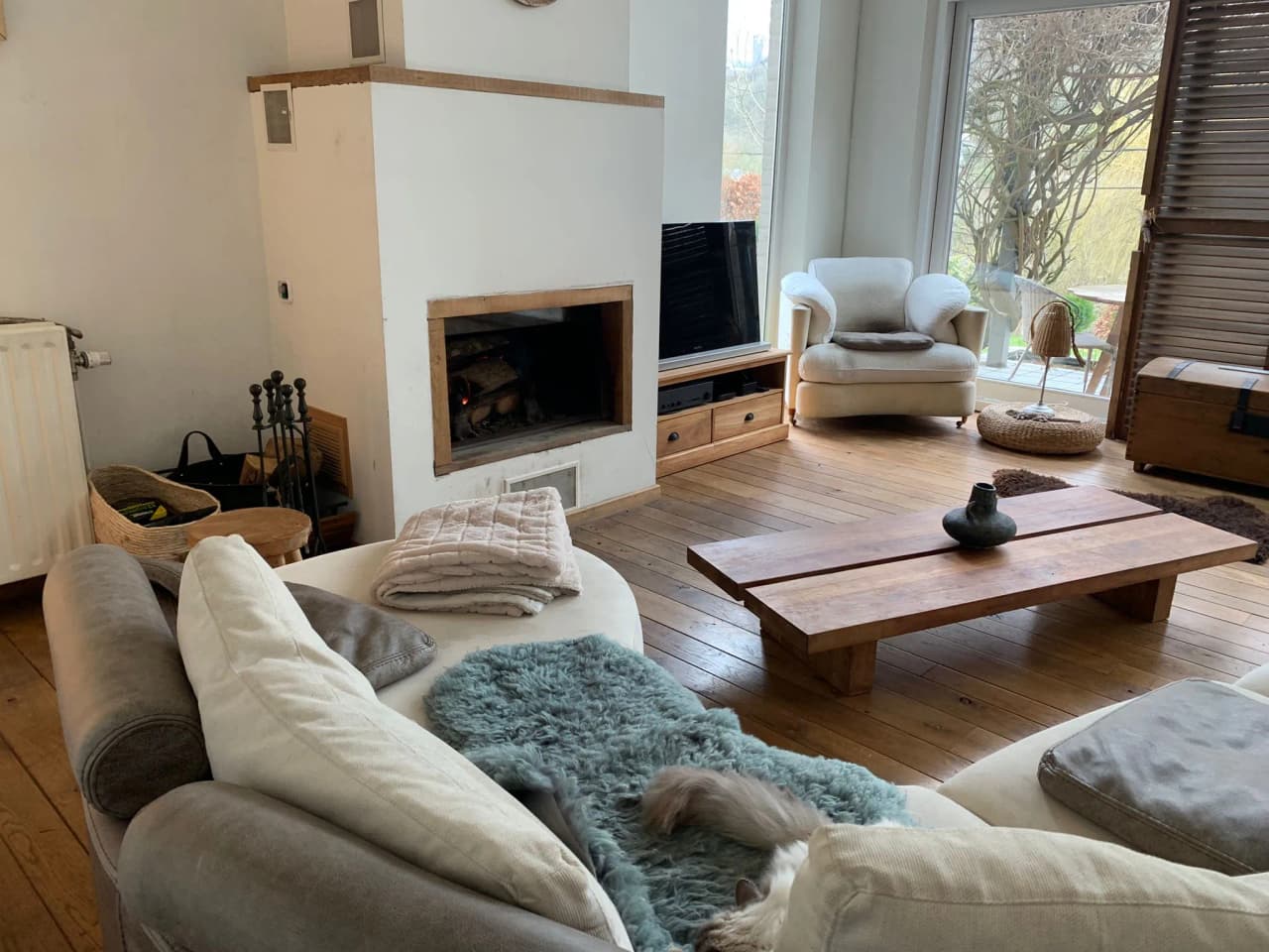 Cosy interior with fireplace, comfortable sofa and natural light, ideal for relaxing.