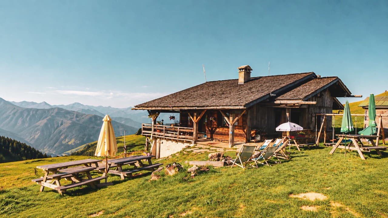 Refuge en bois pittoresque entouré de verdure, offrant une vue imprenable sur les sommets alpins.