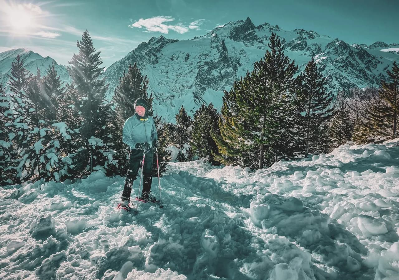 Een sneeuwschoenwandelaar in prachtige verse sneeuw, met uitzicht op de majestueuze bergen onder een heldere hemel.