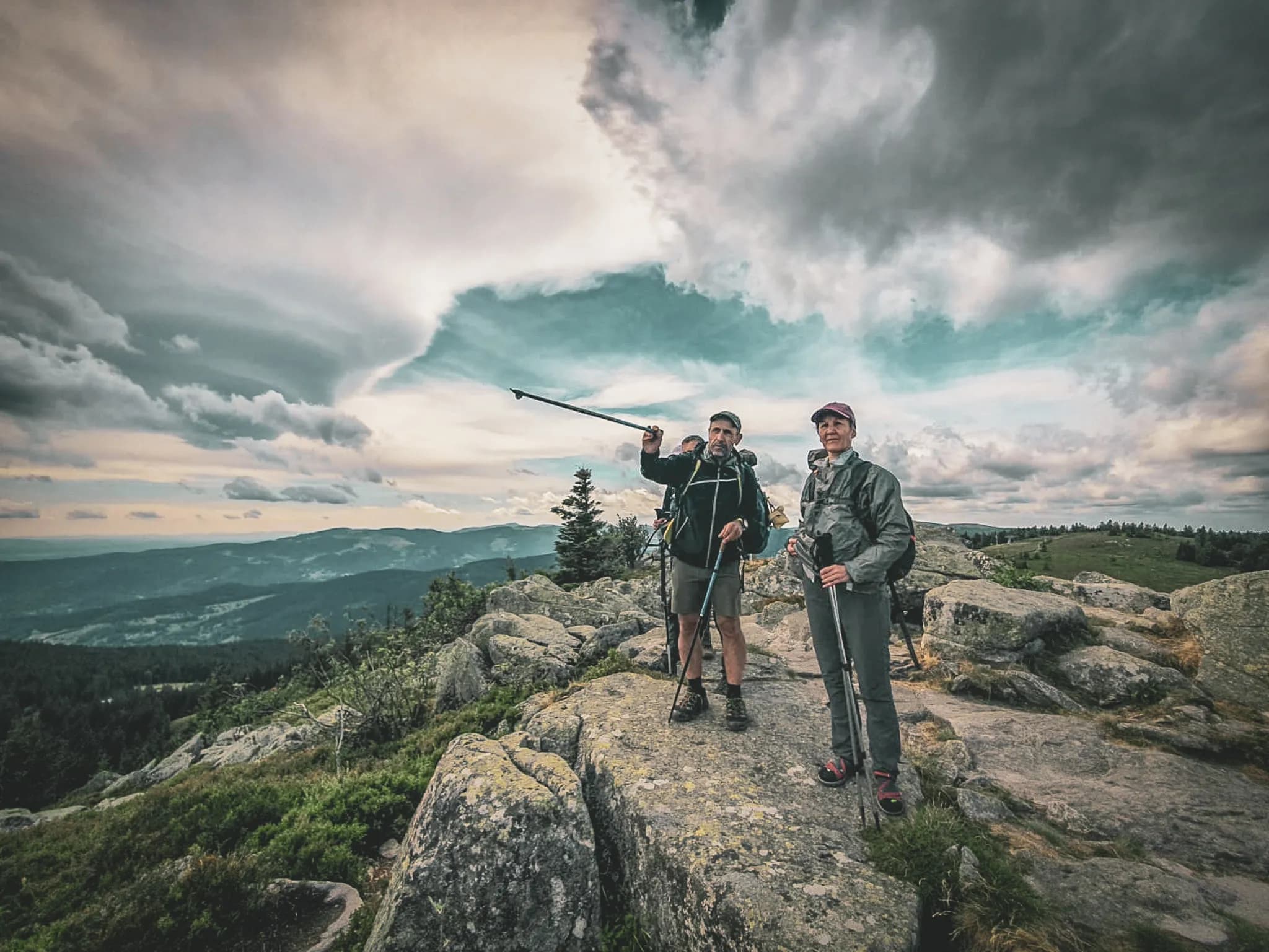 A group of hikers admiring the view from the crests of the Vosges mountains, cloudy skies and splendid scenery.