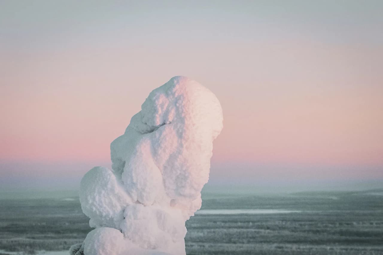 Un mystérieux paysage hivernal en Laponie, avec un amas de neige sur fond pastel, invitant à l'aventure.