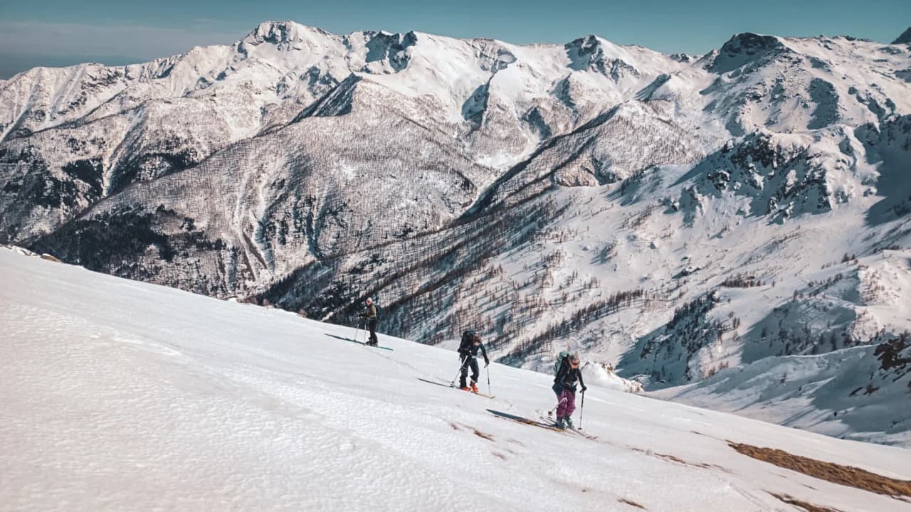 Groupe de skieurs de randonnée traversant des paysages enneigés majestueux autour du Mont Viso.