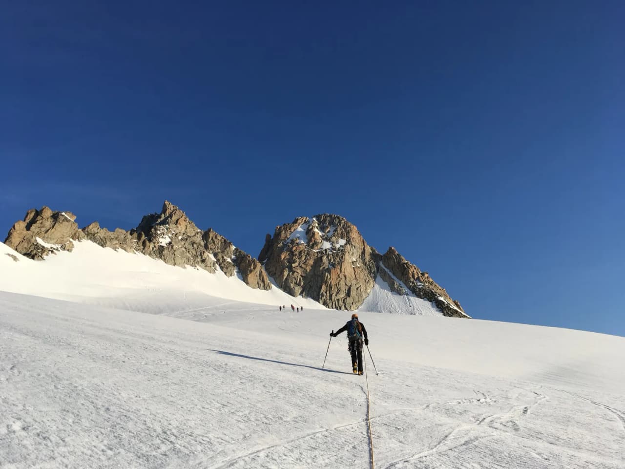 A climber steps out onto a luminous glacier, surrounded by majestic rocky mountains.