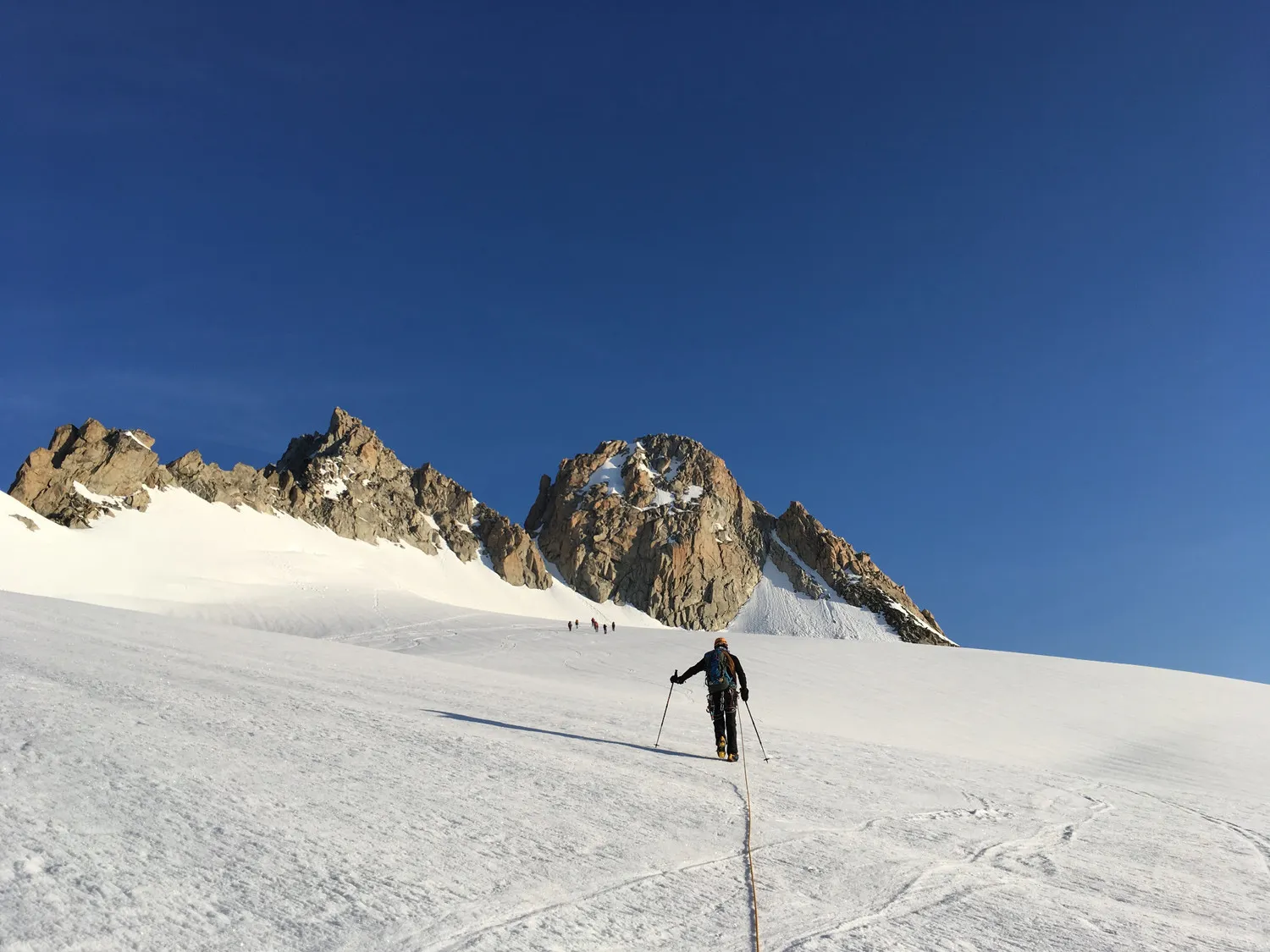 A climber steps out onto a luminous glacier, surrounded by majestic rocky mountains.