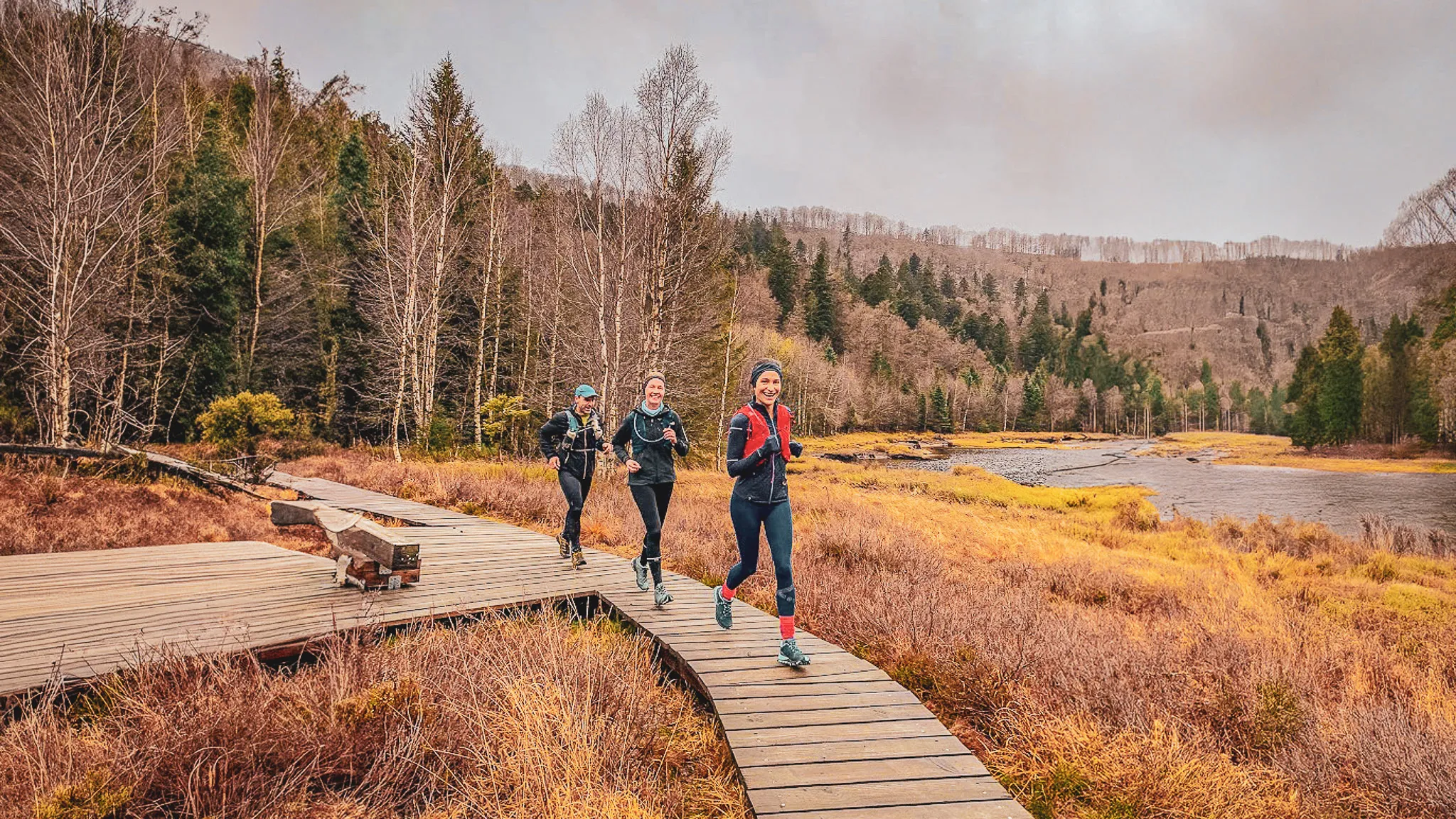 Trois coureuses sur un sentier en bois, entourées de nature, dans les Vosges, prêtes pour l'aventure.