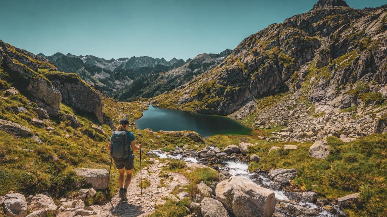 Magnificent Pyrenean scenery, with a high-altitude lake surrounded by lush green mountains.