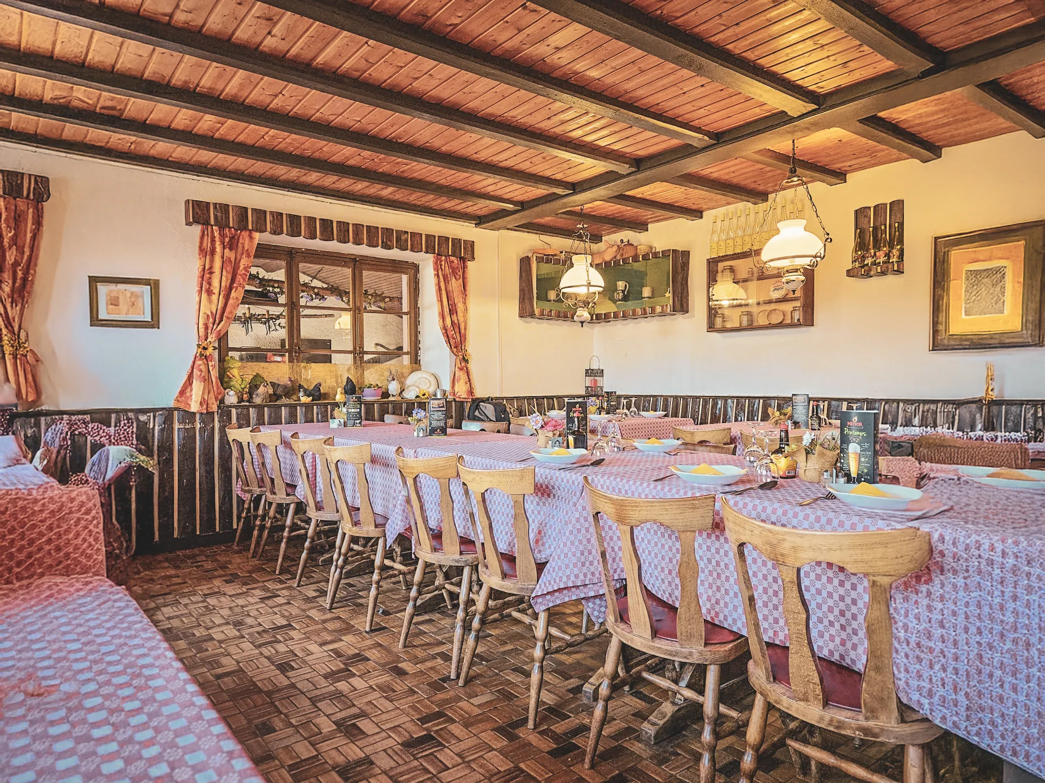 Une salle chaleureuse avec de grandes tables en bois, prête pour un repas convivial après la randonnée.