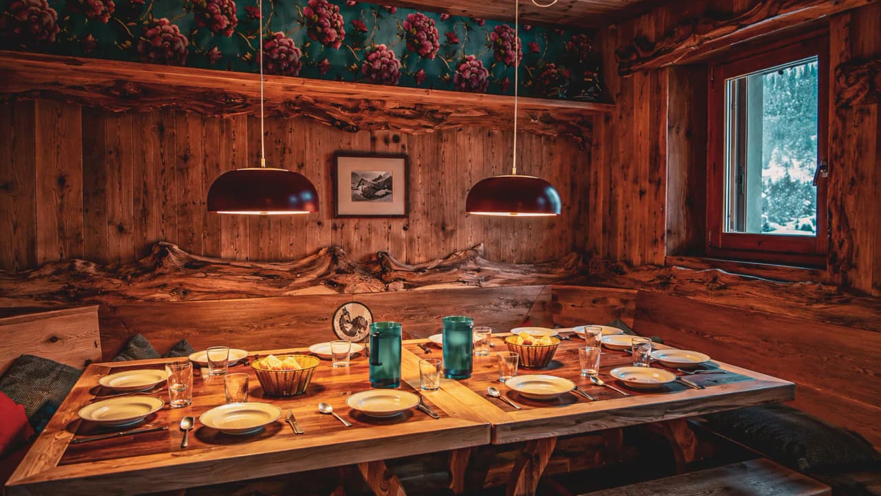 A cosy corner with a wooden table, elegant crockery and hanging lights, perfect for an Alpine meal.