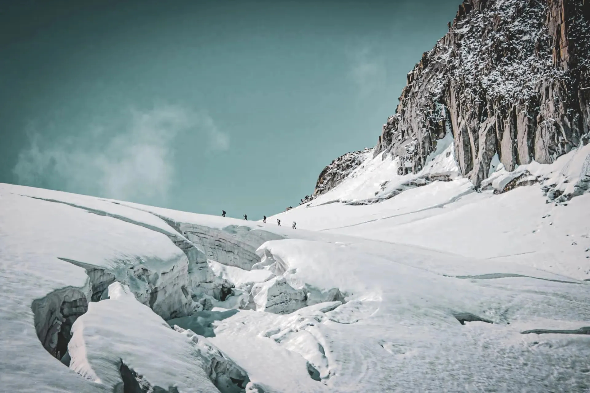 Une équipe d'alpinistes progresse sur un glacier scintillant sous un ciel azur.
