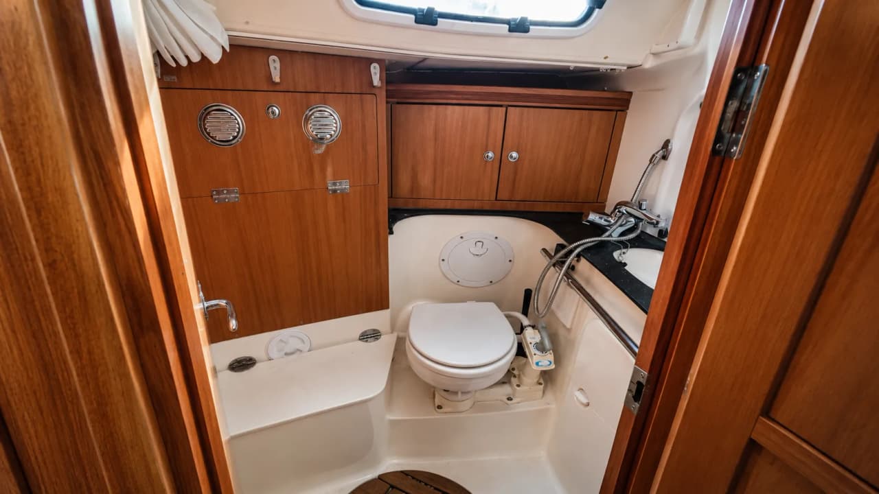 Badkamer van een moderne zeilboot, met warm hout en scheepsuitrusting, perfect voor een avontuur in de fjorden.