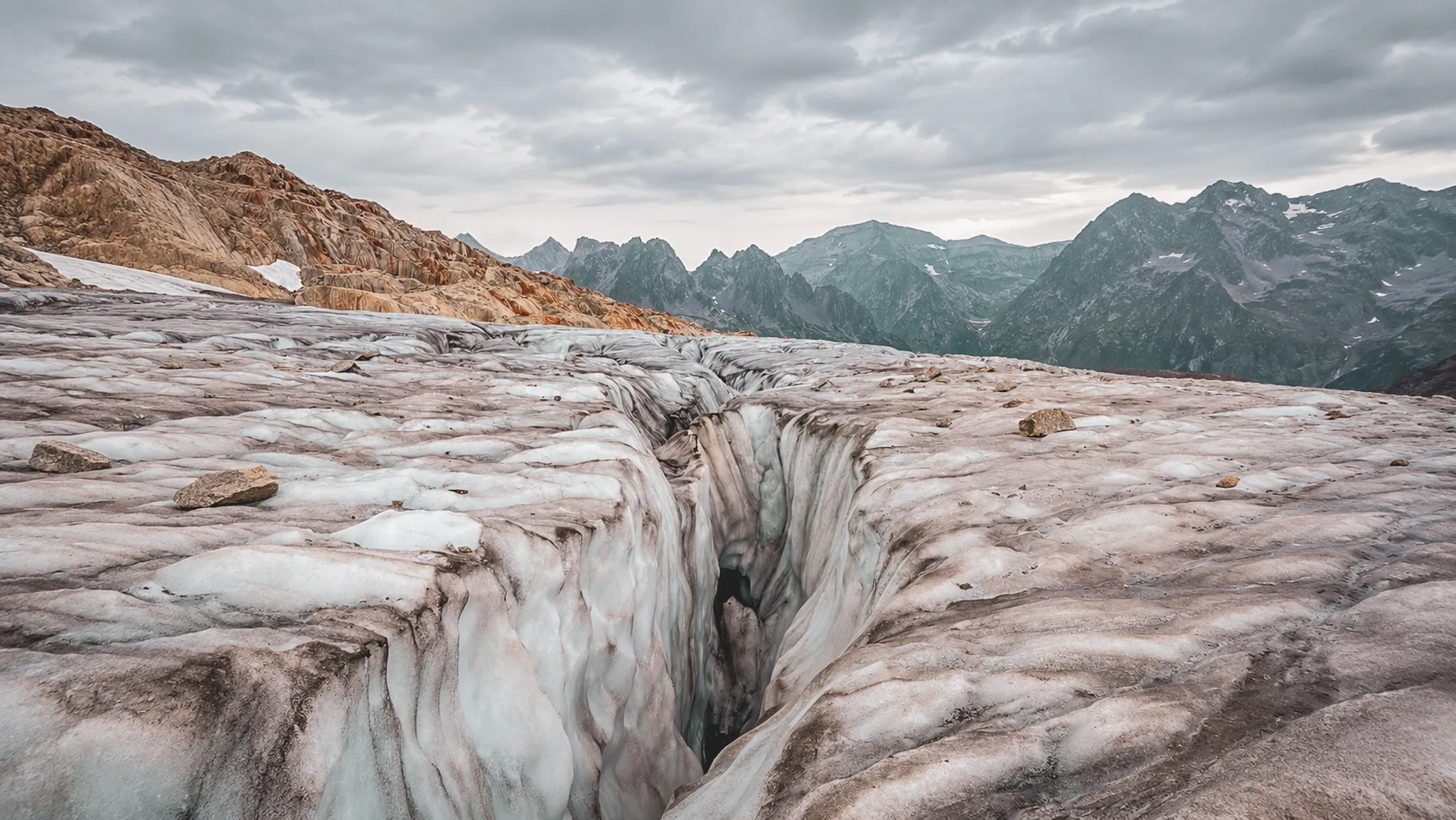 Glacier majestueux au sommet des Alpes, crevasses impressionnantes sous un ciel nuageux.