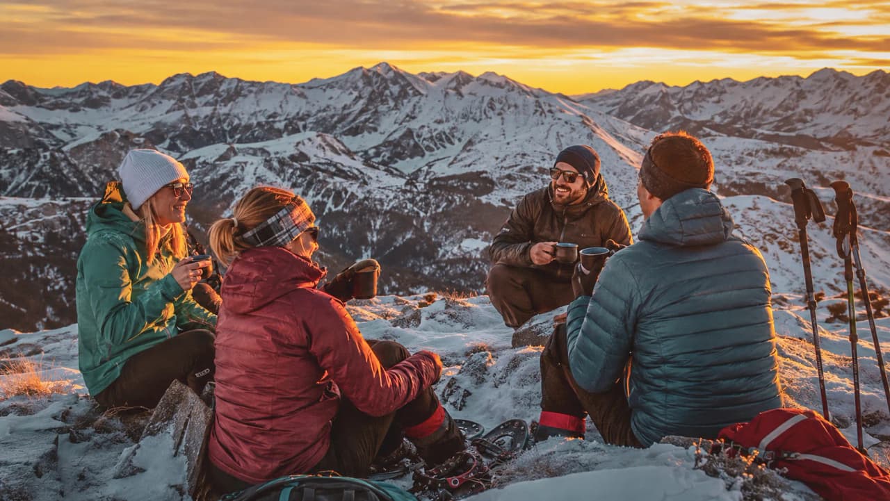 A group of friends are enjoying a cosy moment high in the mountains, watching the sunset.