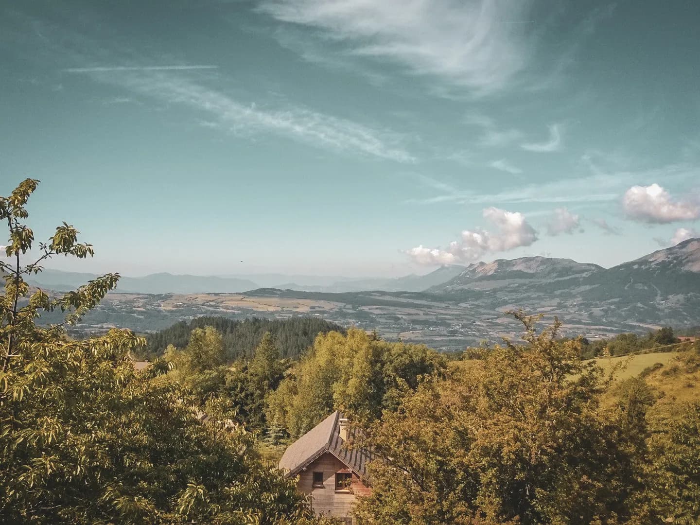 A picturesque Alpine landscape with lush green valleys and majestic mountains, an invitation to travel.