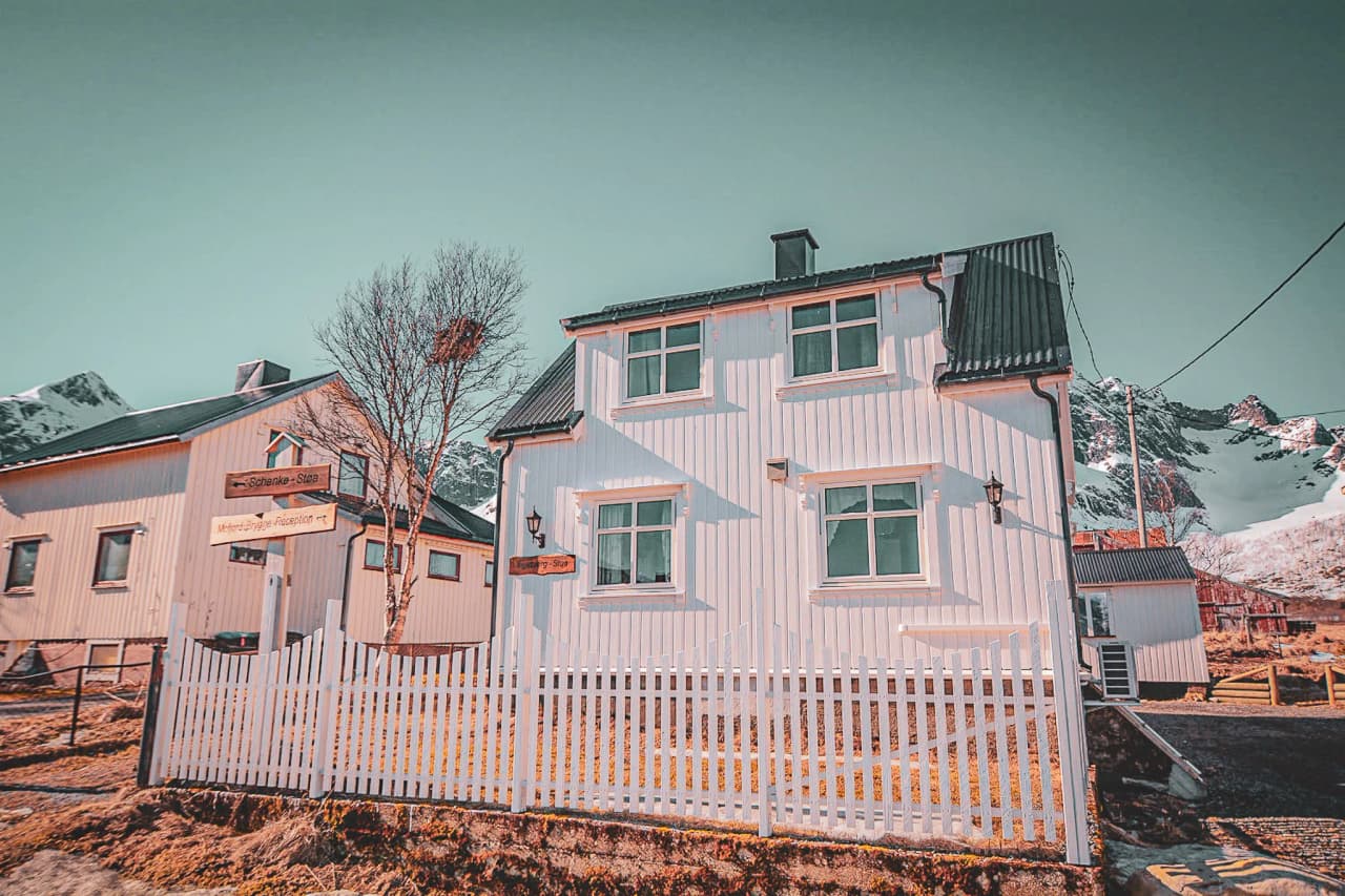 Een pittoresk wit huis op het eiland Senja, omringd door majestueuze bergen.