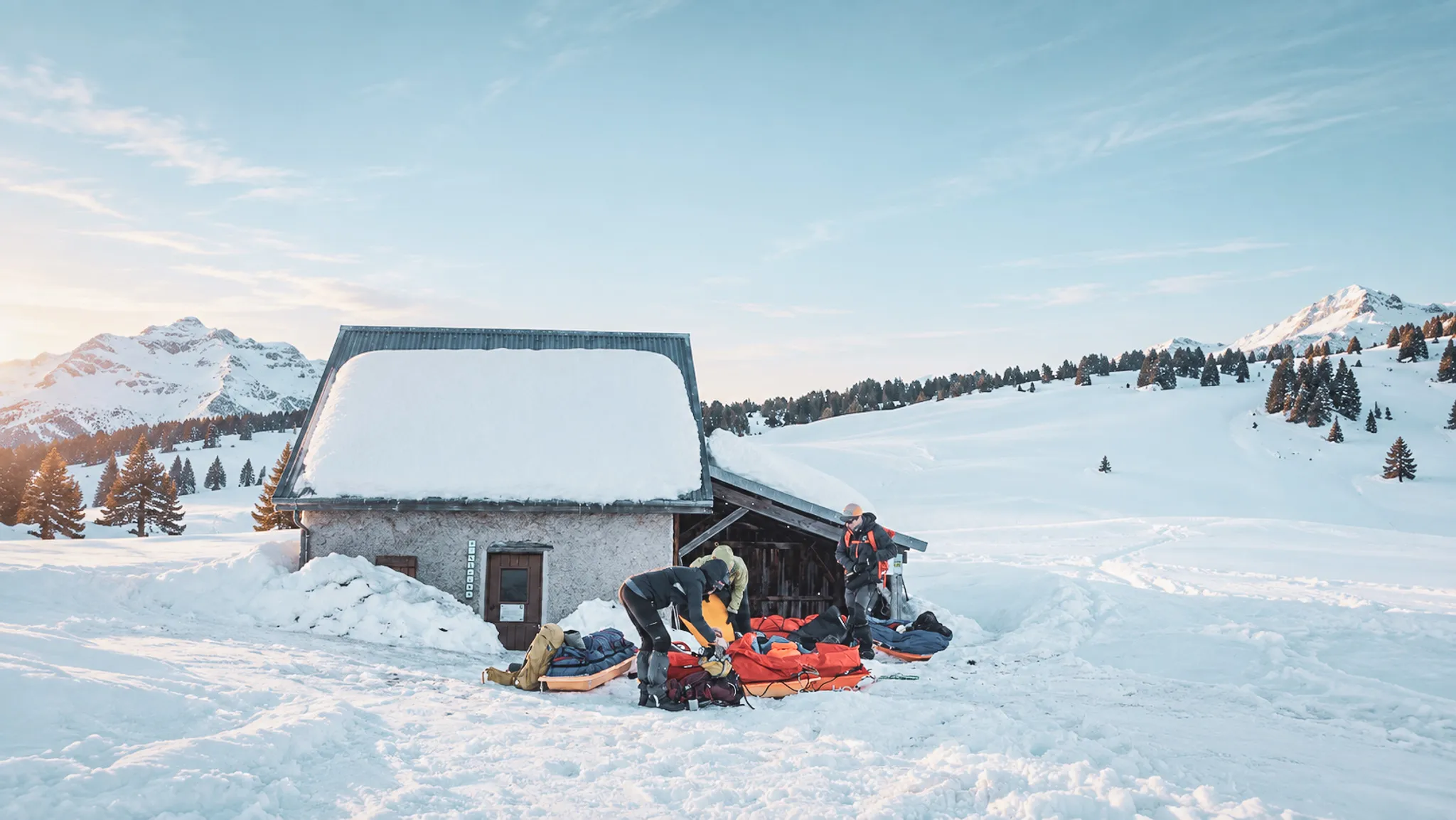 Un groupe prépare son équipement devant un chalet enneigé, plongé dans les paysages du Vercors.