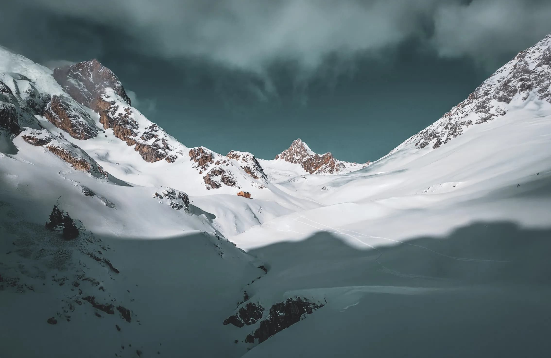 Paysage alpin majestueux, montagnes enneigées et ciel dramatique, invitation à l'aventure.