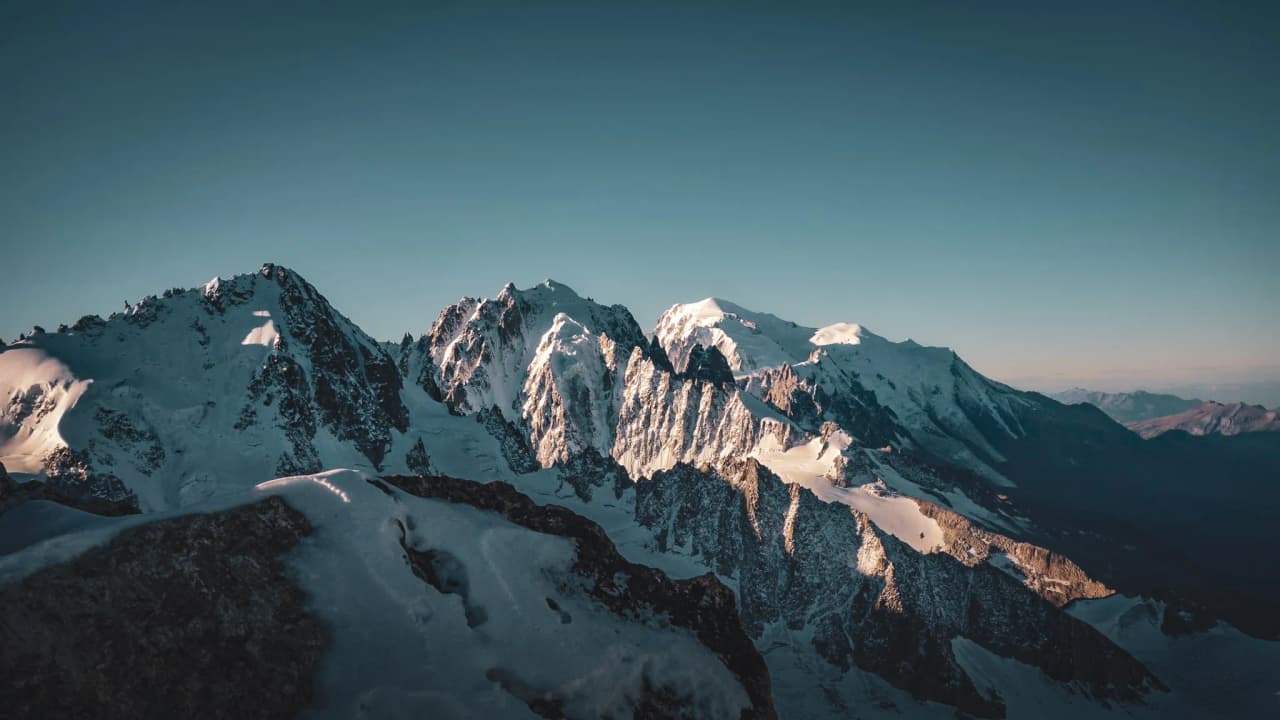 A majestic panorama of the Alps, snow-capped peaks and glaciers under a clear sky, an invitation to travel.