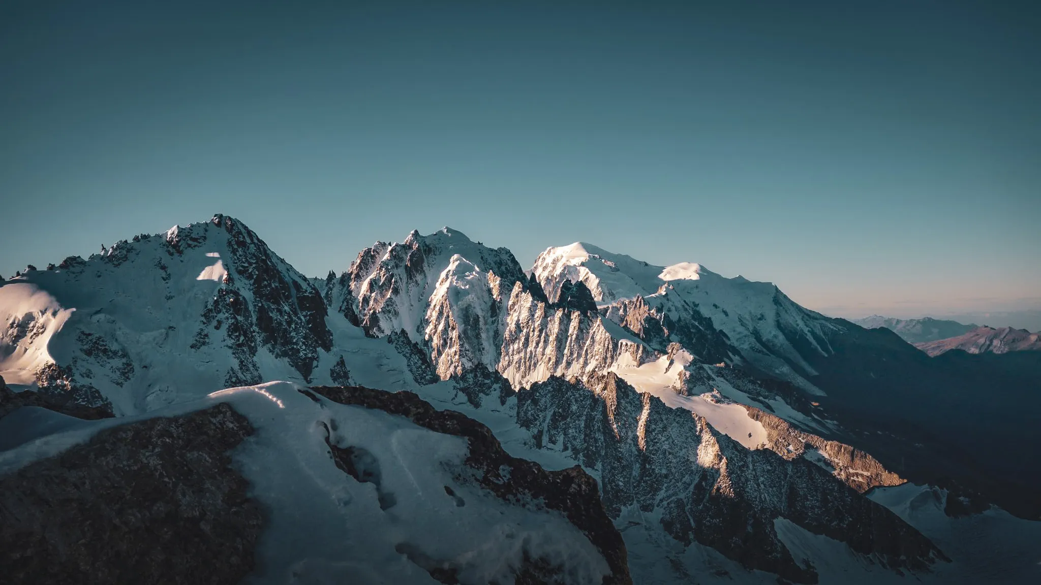 A majestic panorama of the Alps, snow-capped peaks and glaciers under a clear sky, an invitation to travel.