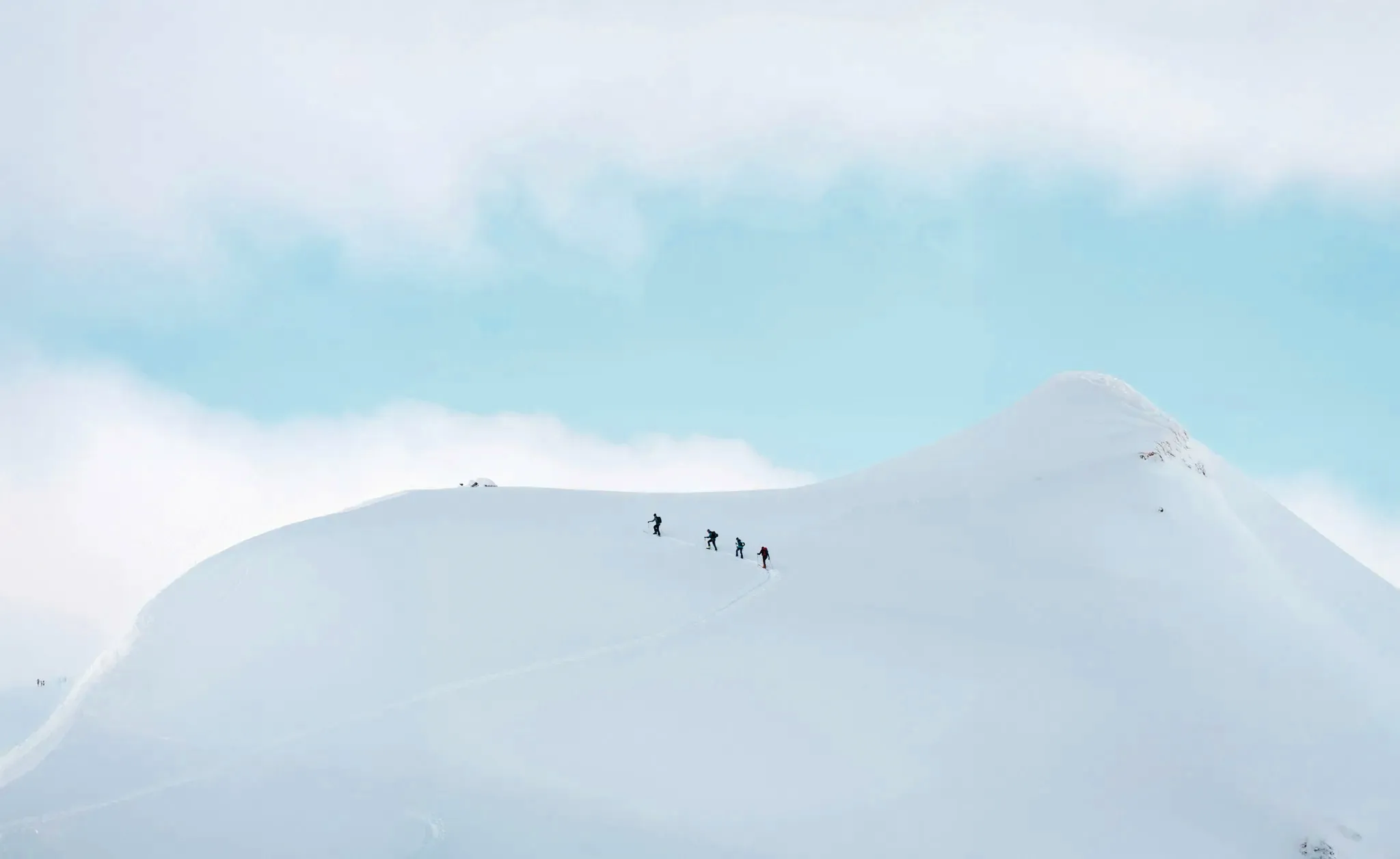A group of skiers on a snowy slope, under a soothing blue sky.