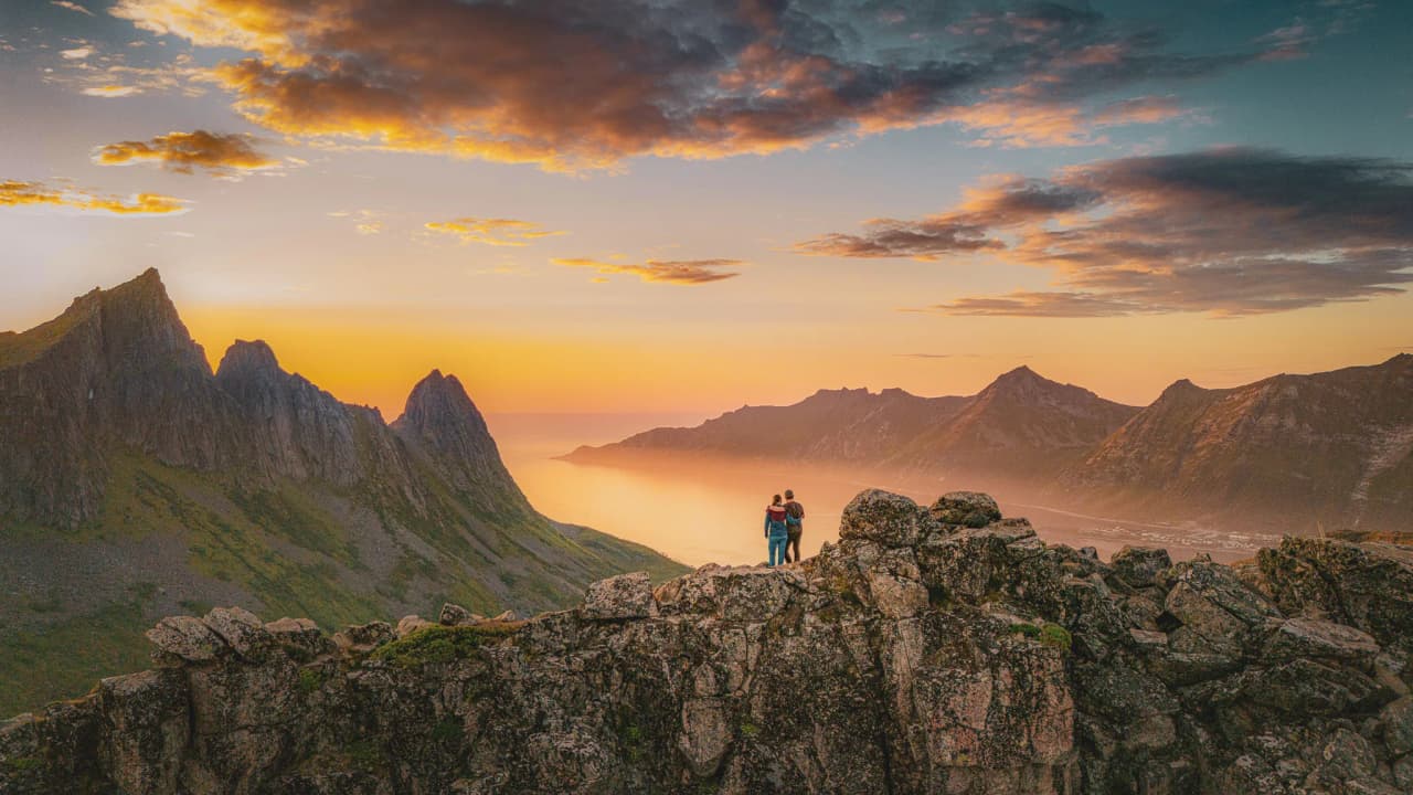Een koppel bewondert een zonsondergang boven de majestueuze bergen van het eiland Senja.