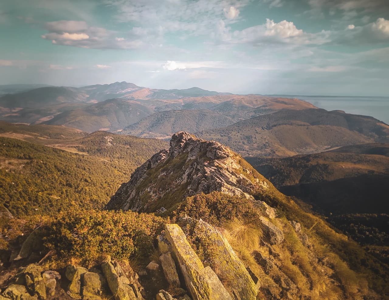Paysage montagneux des Pyrénées avec sommets majestueux, végétation verdoyante et ciel ensoleillé.